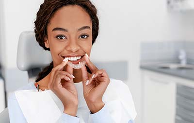 woman holding her Invisalign clear aligners